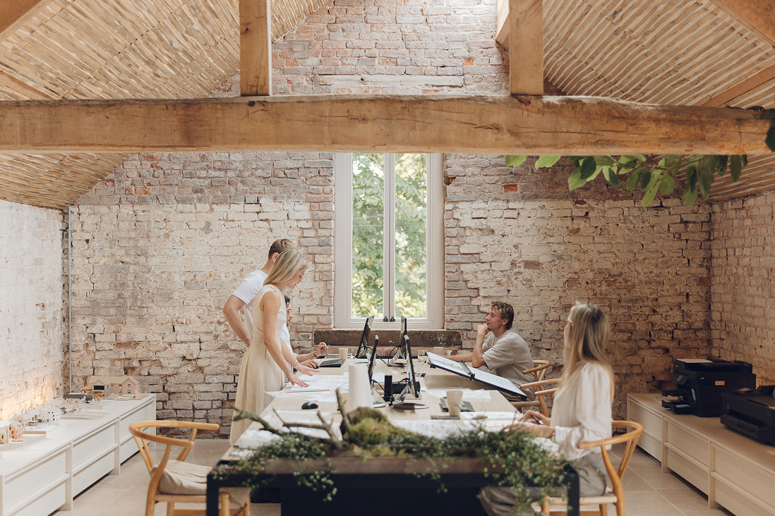 The team reviewing drawings around a table in a barn interior