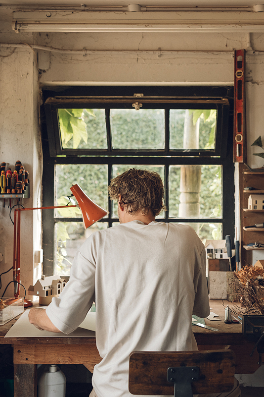 Architect working at a bench beneath the workshop window